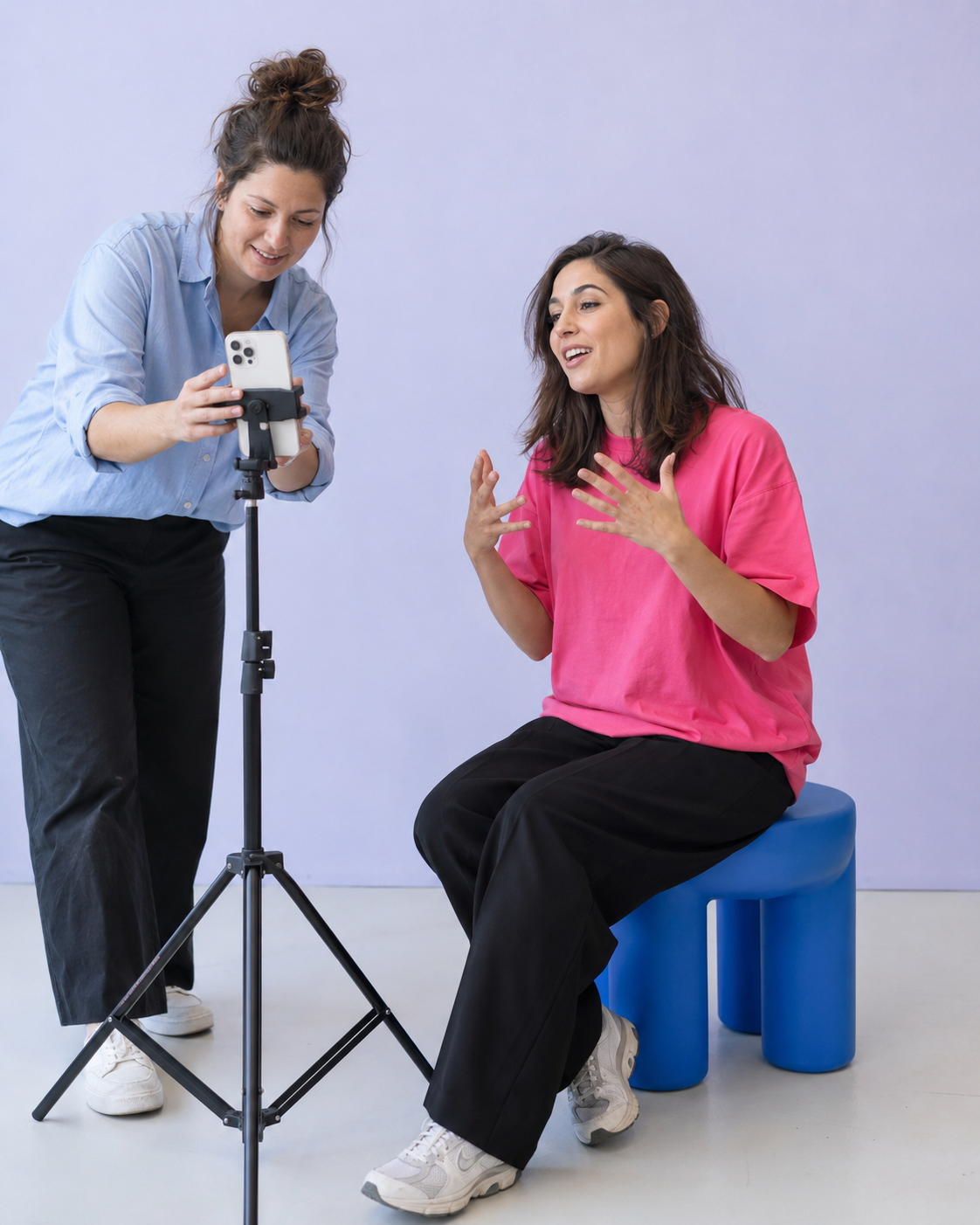 Two creators practising filming with a phone in a bright lavender studio